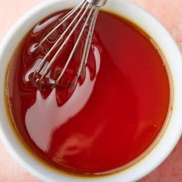 Top-down view of a bowl of golden syrup with a whisk in.