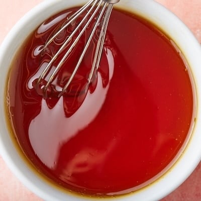 Top-down view of a bowl of golden syrup with a whisk in.