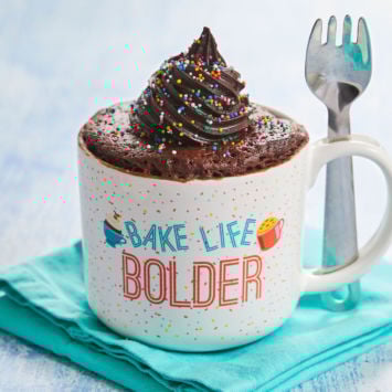 The Best-Ever Chocolate Mug Cake piled high with frosting in my Bigger Bolder Baking Mug Meals Mug with Spork!