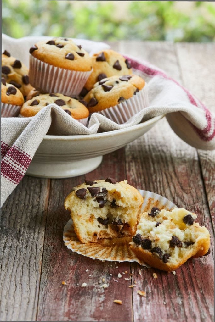 A Classic Chocolate Chip Muffin broken open to show interior texture and chocolate chips.