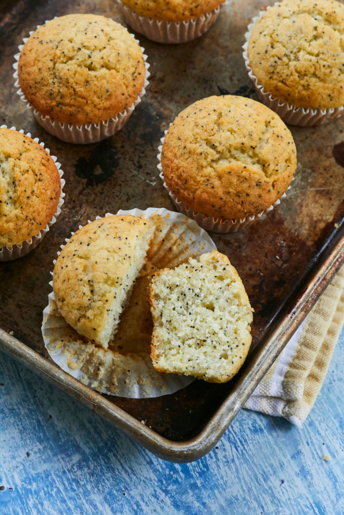 A closeup and cross section of Lemon Poppyseed Muffins, showing color and texture.