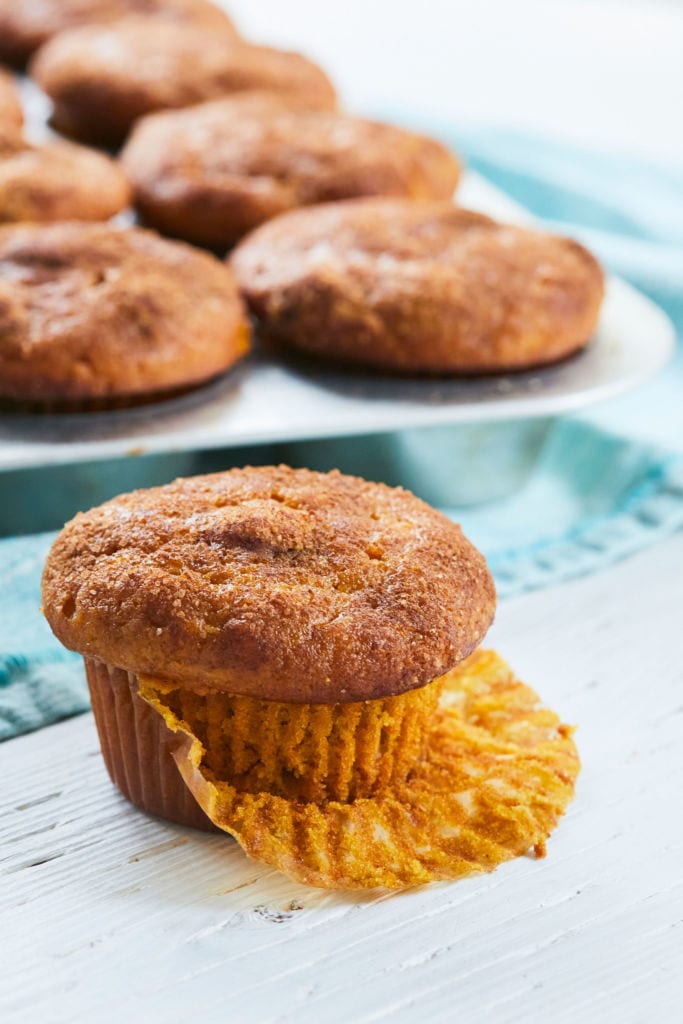 A Chocolate Chip Pumpkin Muffin with the wrapper peeled back, showing texture and color.