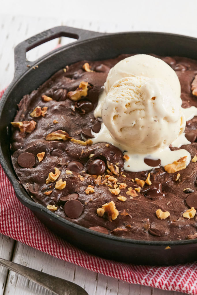 A Skillet Brownies recipe topped with ice cream and nuts.