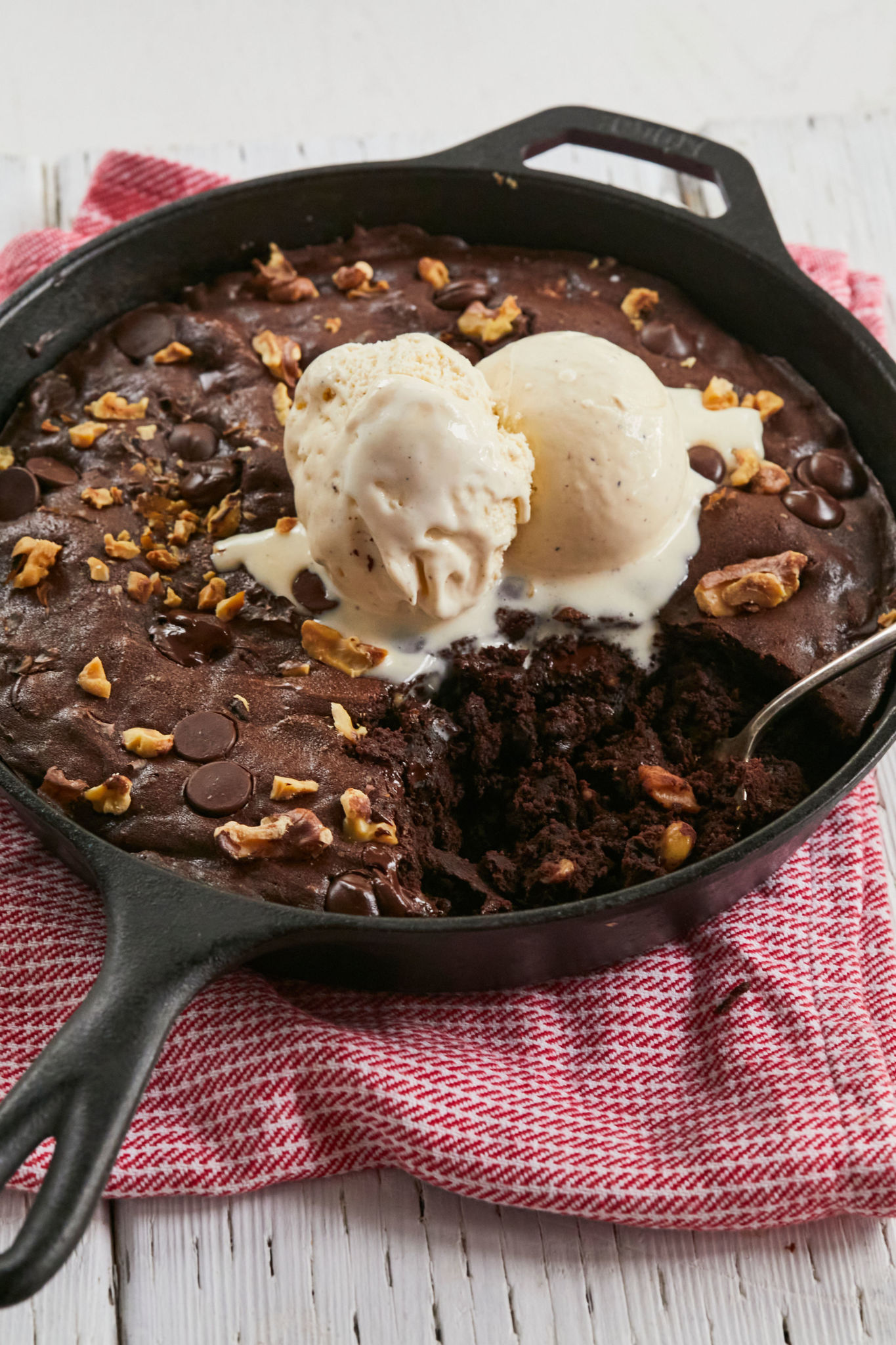 Skillet Brownies are topped with ice cream, packed with chocolate chips and nuts. 