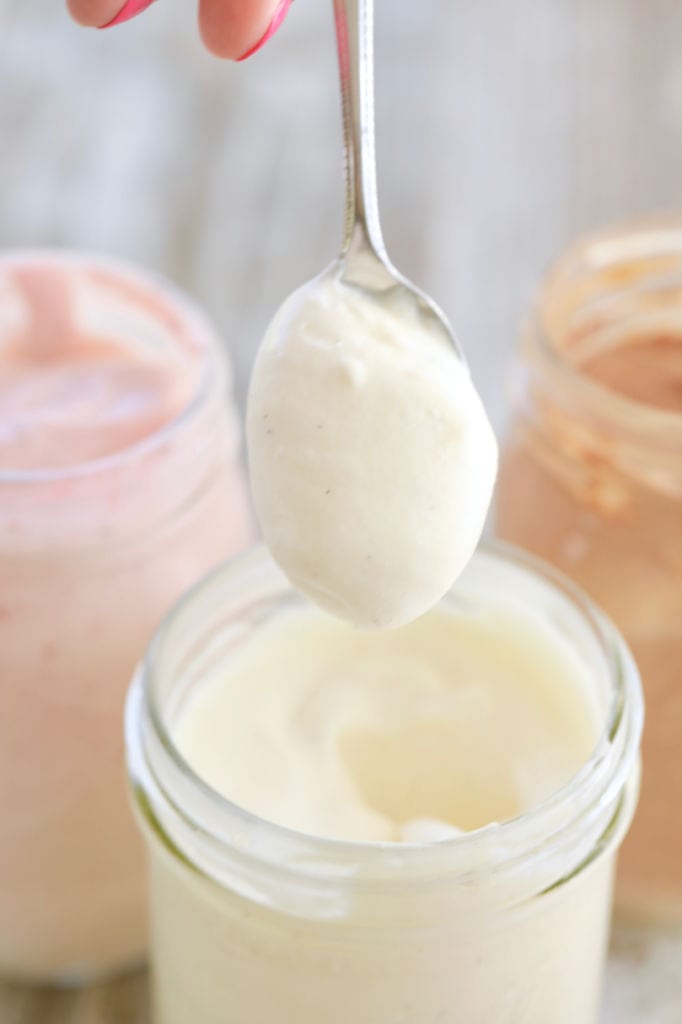 A spoon showing the texture of homemade vanilla ice cream made in a jar.