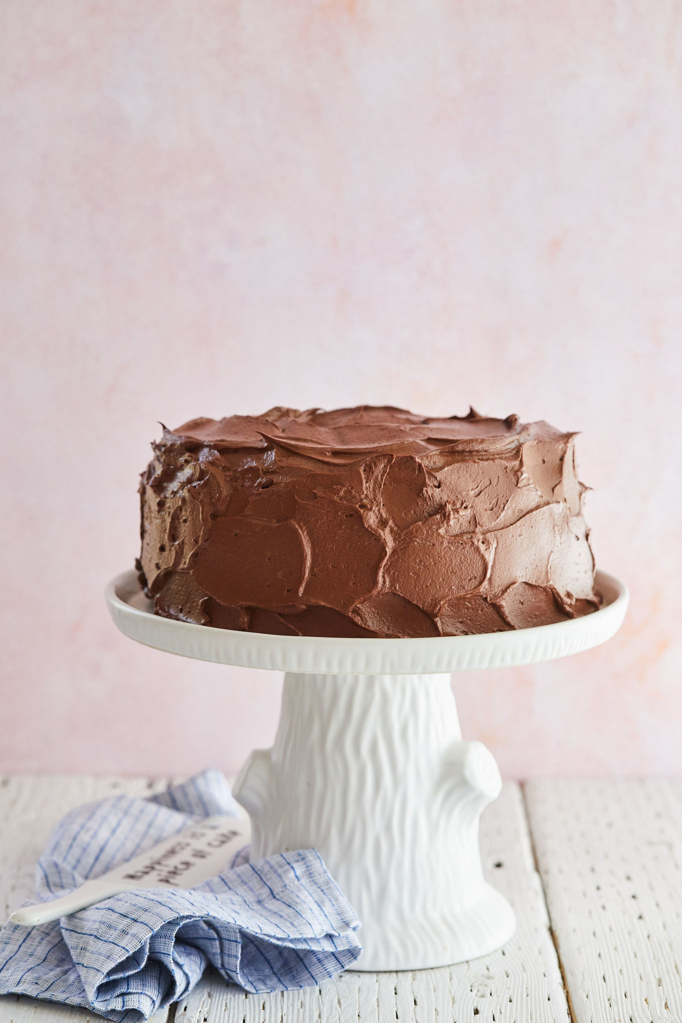 A finished Best-Ever Chocolate Cake on a cake stand with whipped ganache.