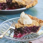 A slice of perfect blueberry pie, topped with whipped cream.
