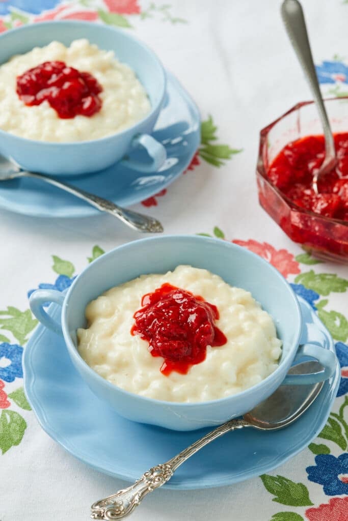 Two bowls of The Creamiest Rice Pudding is served with raspberry jam.