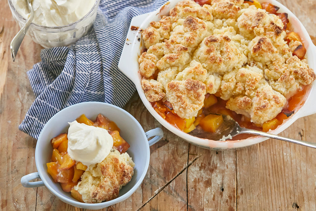 A serving of Best Peach Cobbler recipe topped with whipped cream.