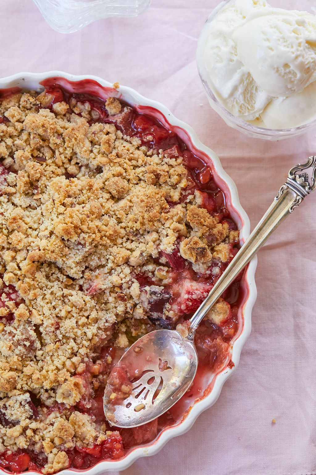 A top-down look at my classic strawberry rhubarb crisp, flanked with vanilla ice cream.