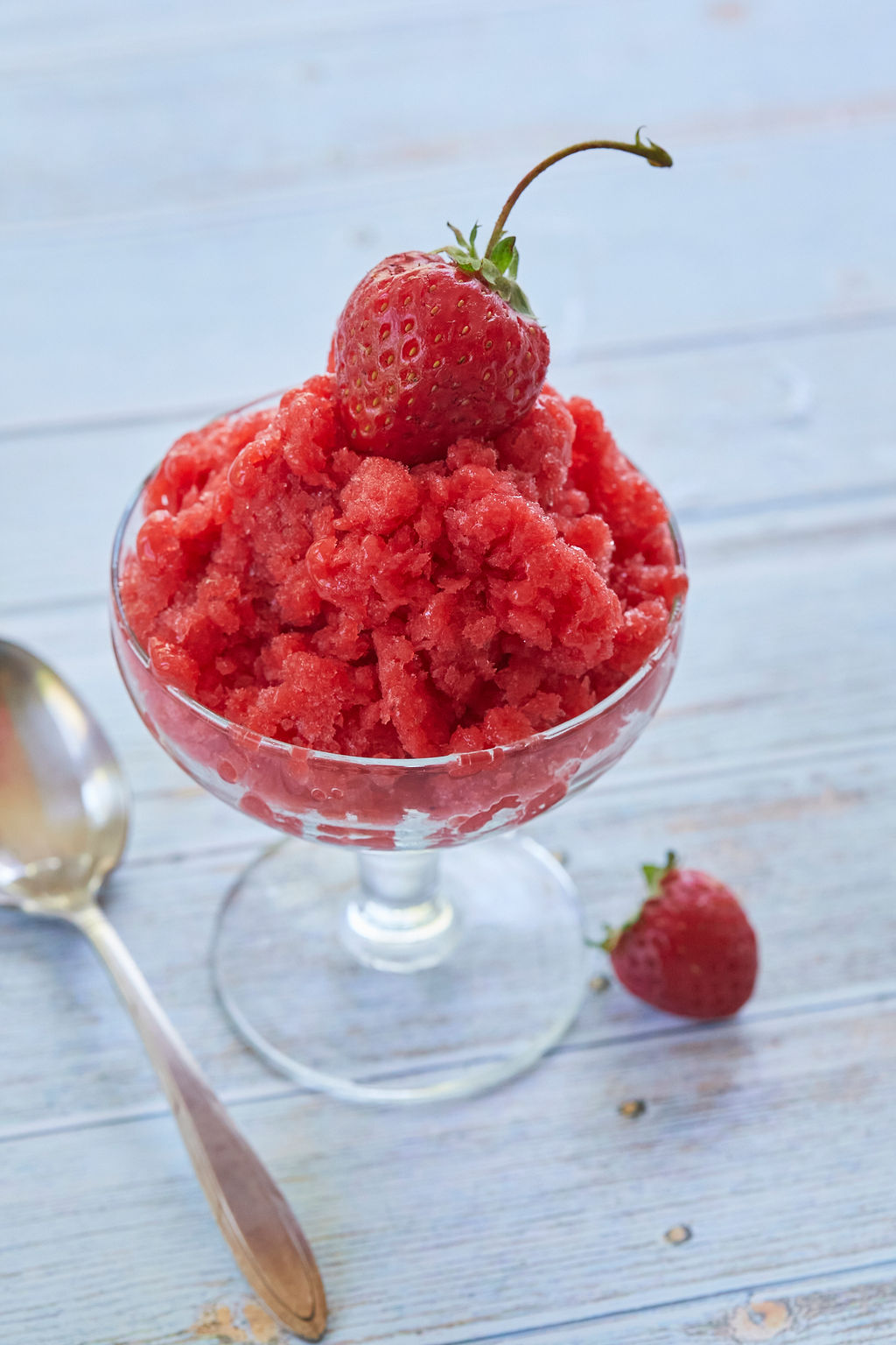 Strawberry Granita served in a dish and topped with a strawberry.