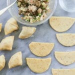 Samosas ready for baking and ready to be made, laid out on a table with a bowl of vegan samosa filling