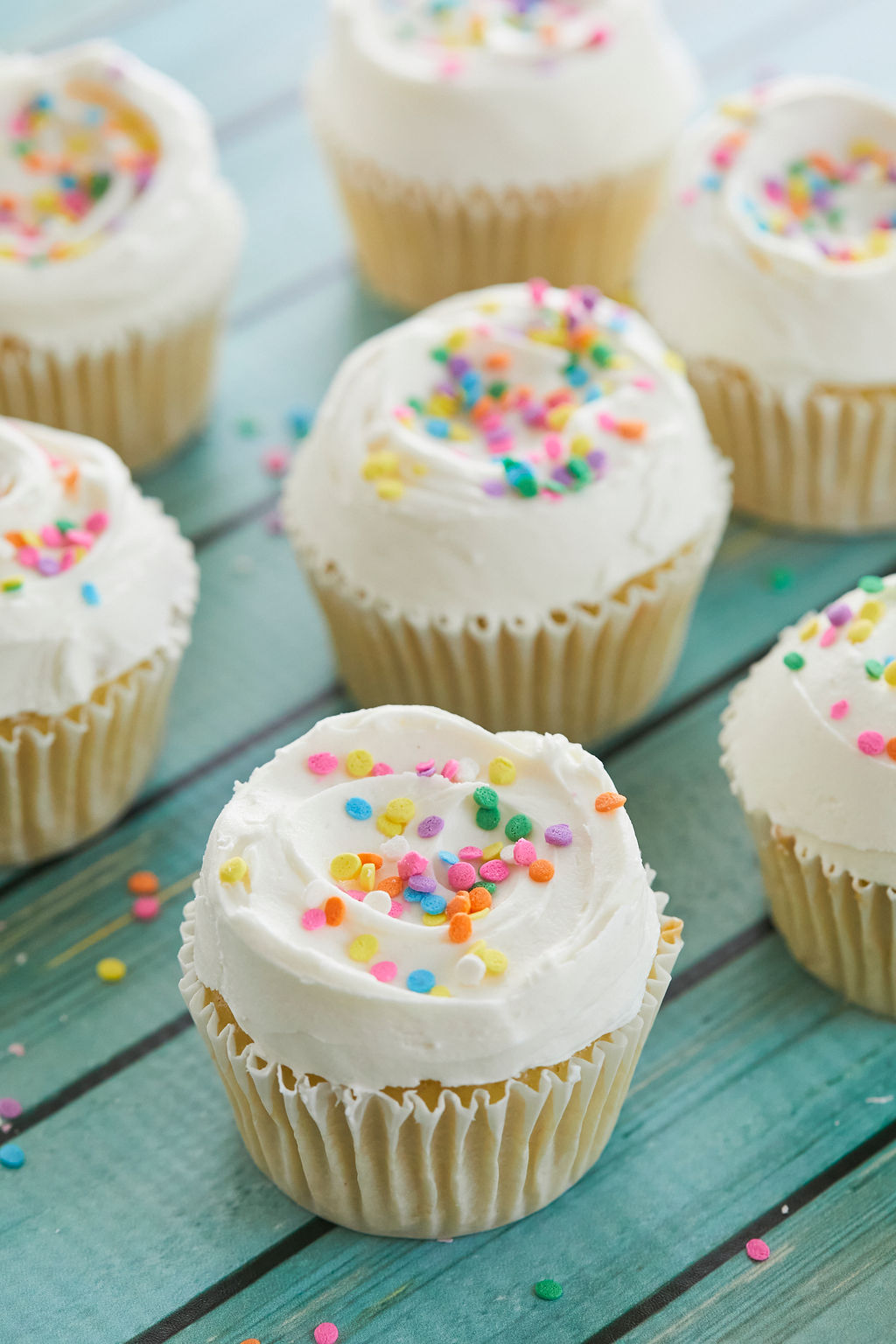 Vanilla cupcakes topped with buttercream and colorful sprinkles.