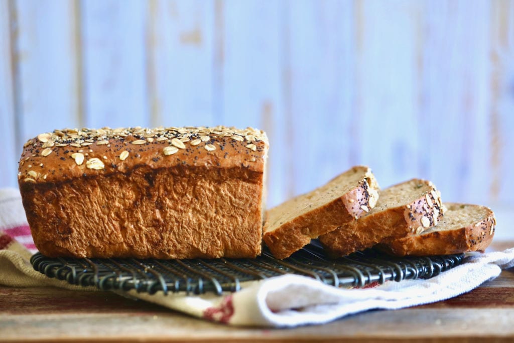 A loaf of whole wheat bread sliced, viewed from the side.