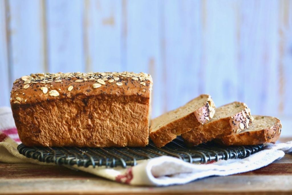 A loaf of whole wheat bread sliced, viewed from the side.