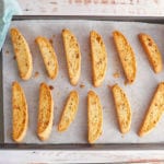 Biscotti lying on a try being held by hands.