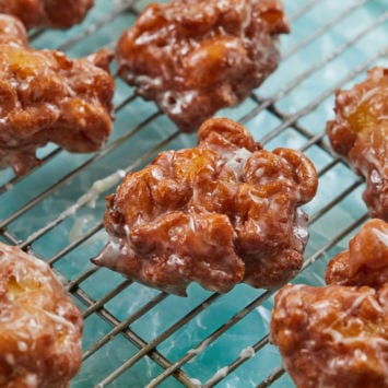 A bunch of apple fritters cooling on a rack.