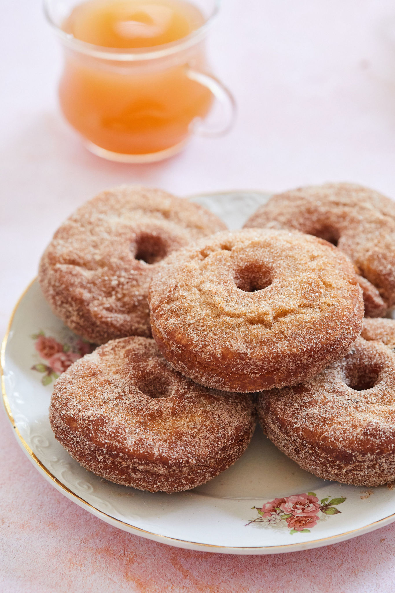 A plate of apple cider donuts covered in cinnamon sugar.