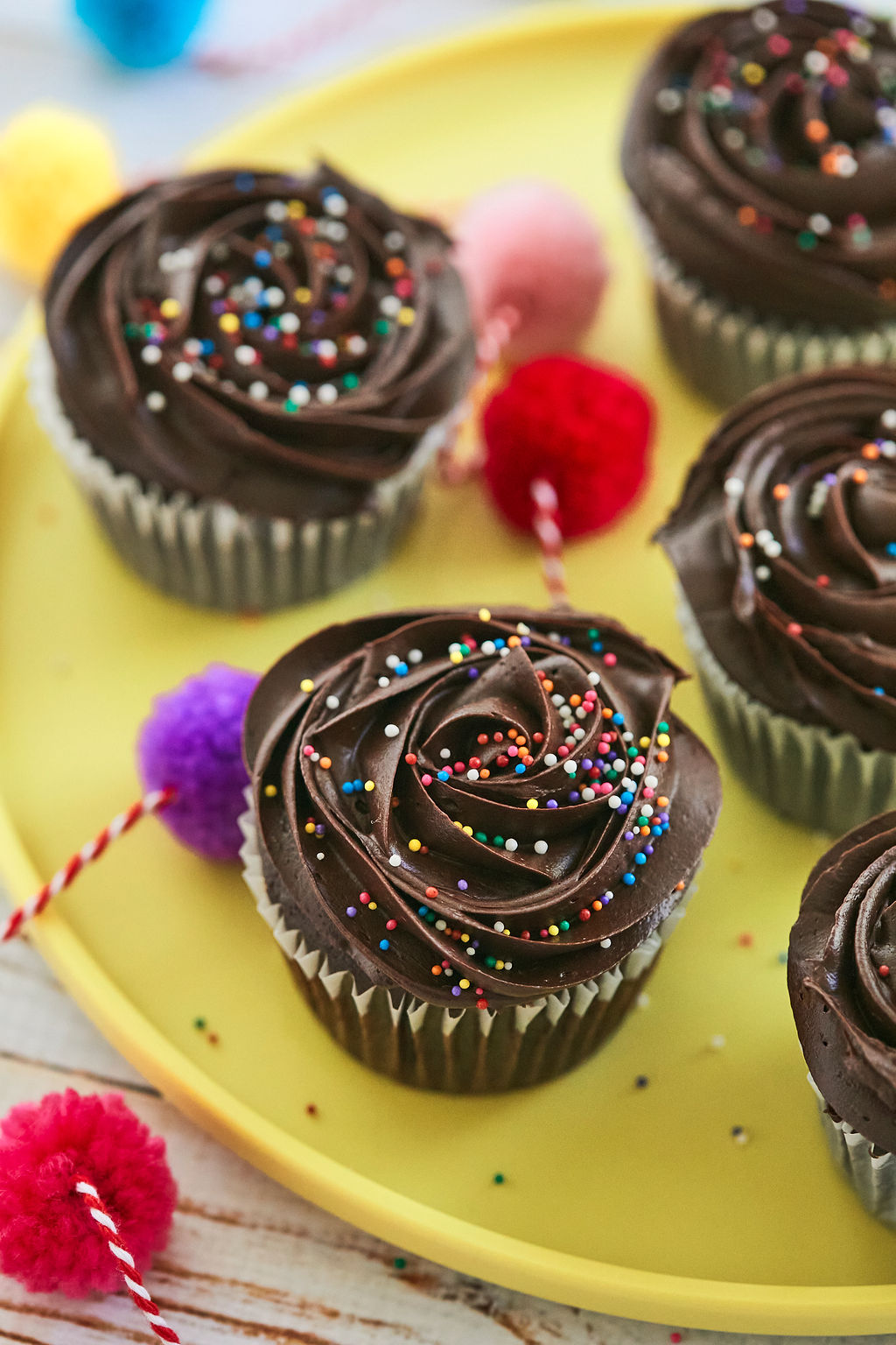 Chocolate Cupcakes with fudge frosting topped with sprinkles.