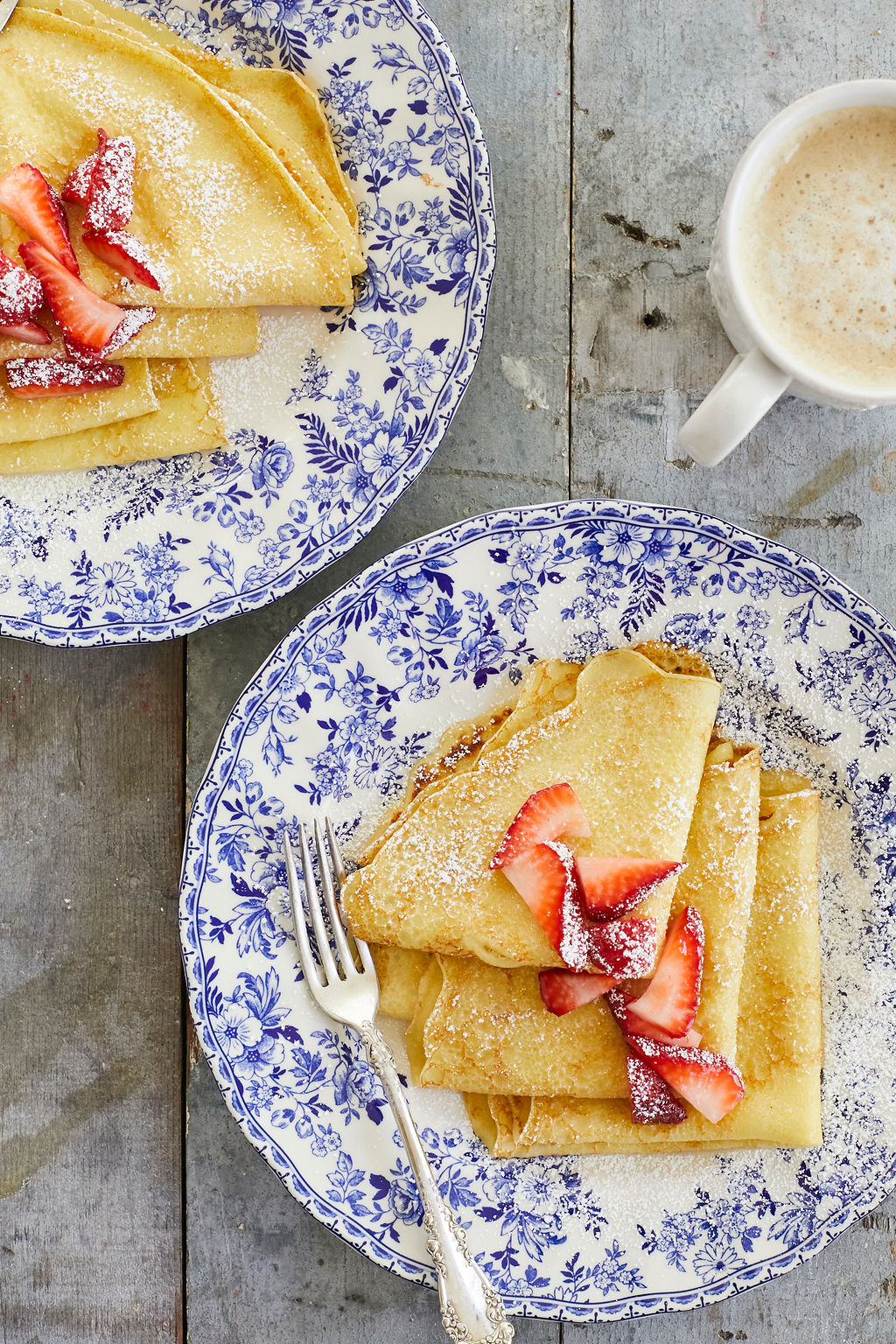 My Crepes recipe dusted in powdered sugar and topped with strawberries.
