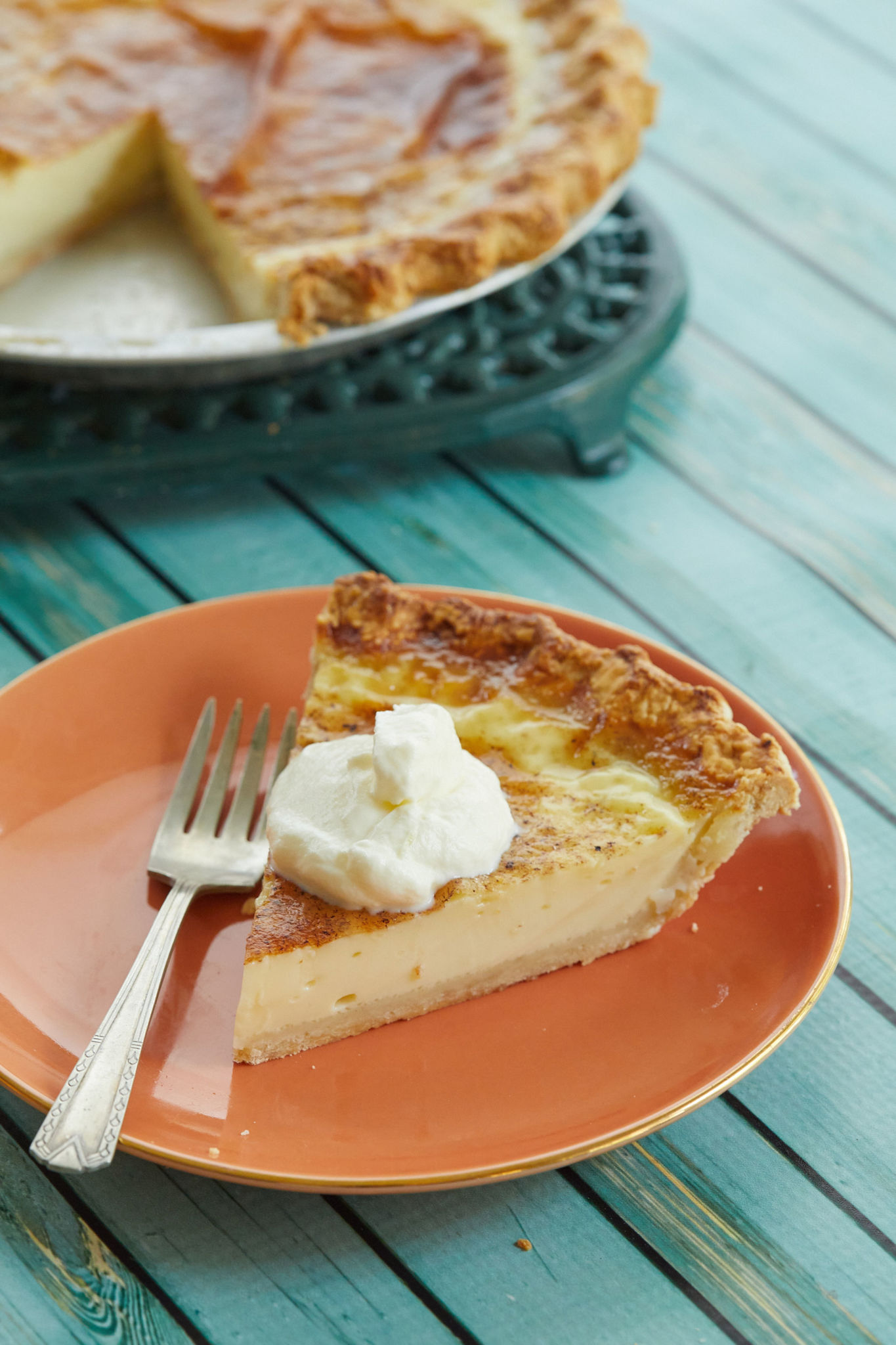 A slice of egg custard pie topped with cream.