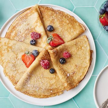 Crepe folded into triangle shapes and served with fresh strawberries and blueberries.