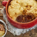A dish of pecan cobbler next to bowls with portions served.