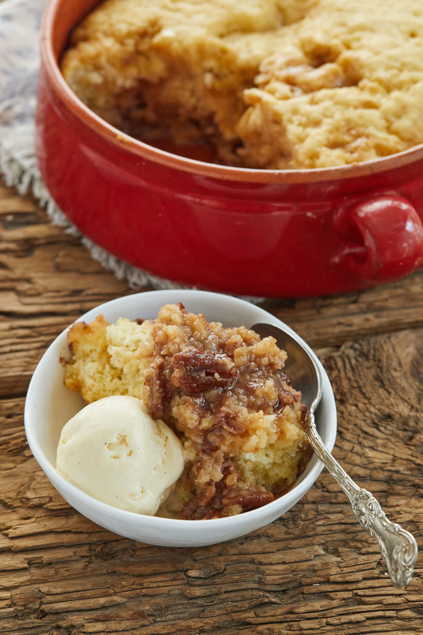 Self saucing pecan cobbler served in a bowl with ice cream.