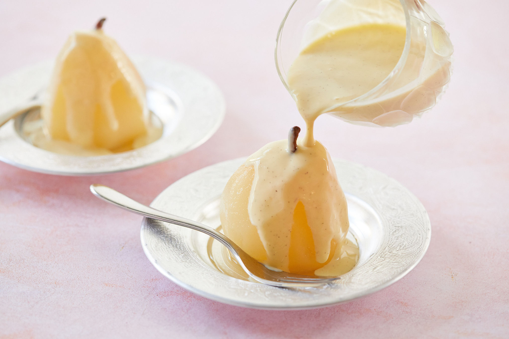 Two poached pears, one with creme anglaise.