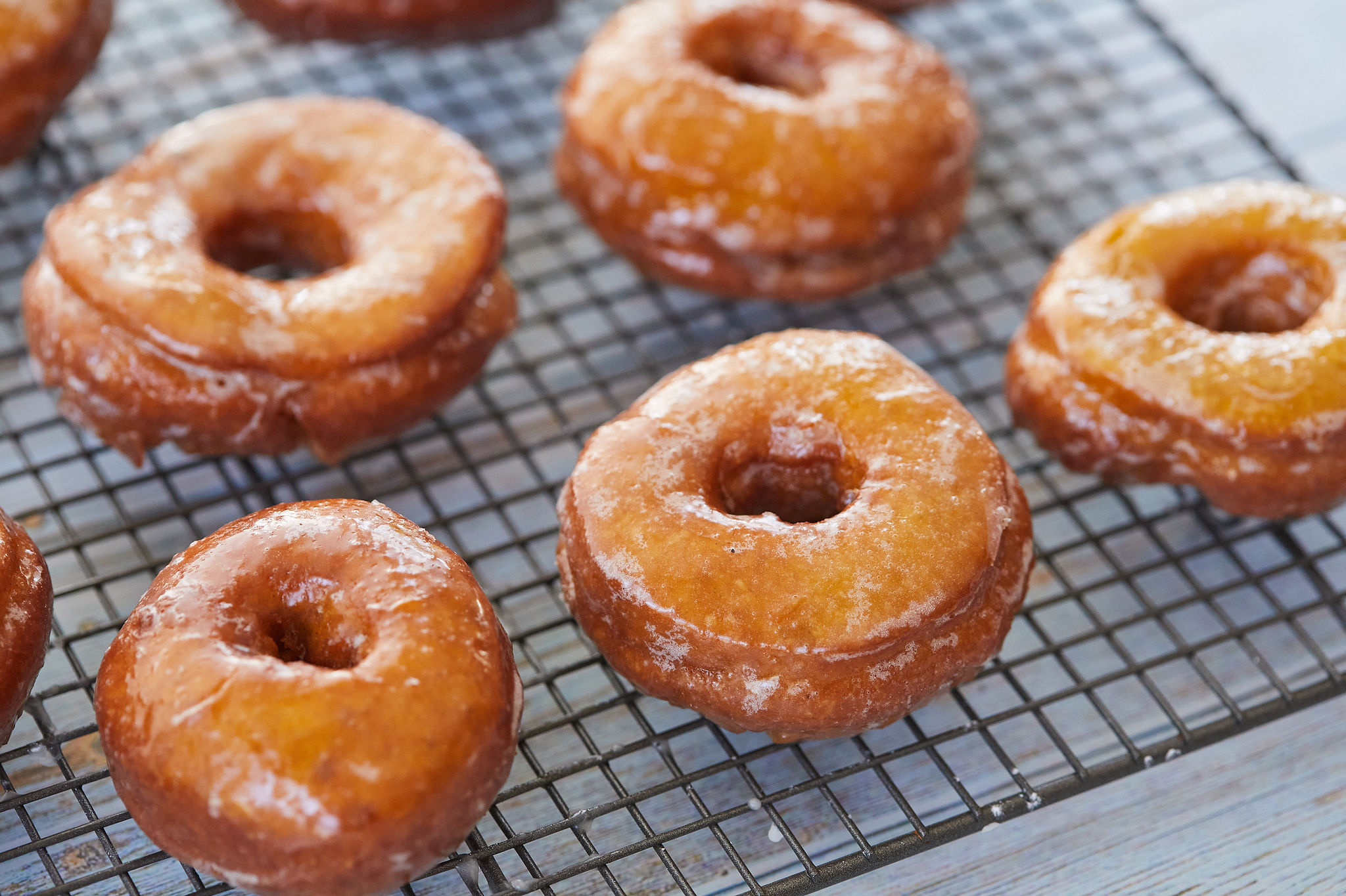A batch of pumpkin donuts cooling on a rack.
