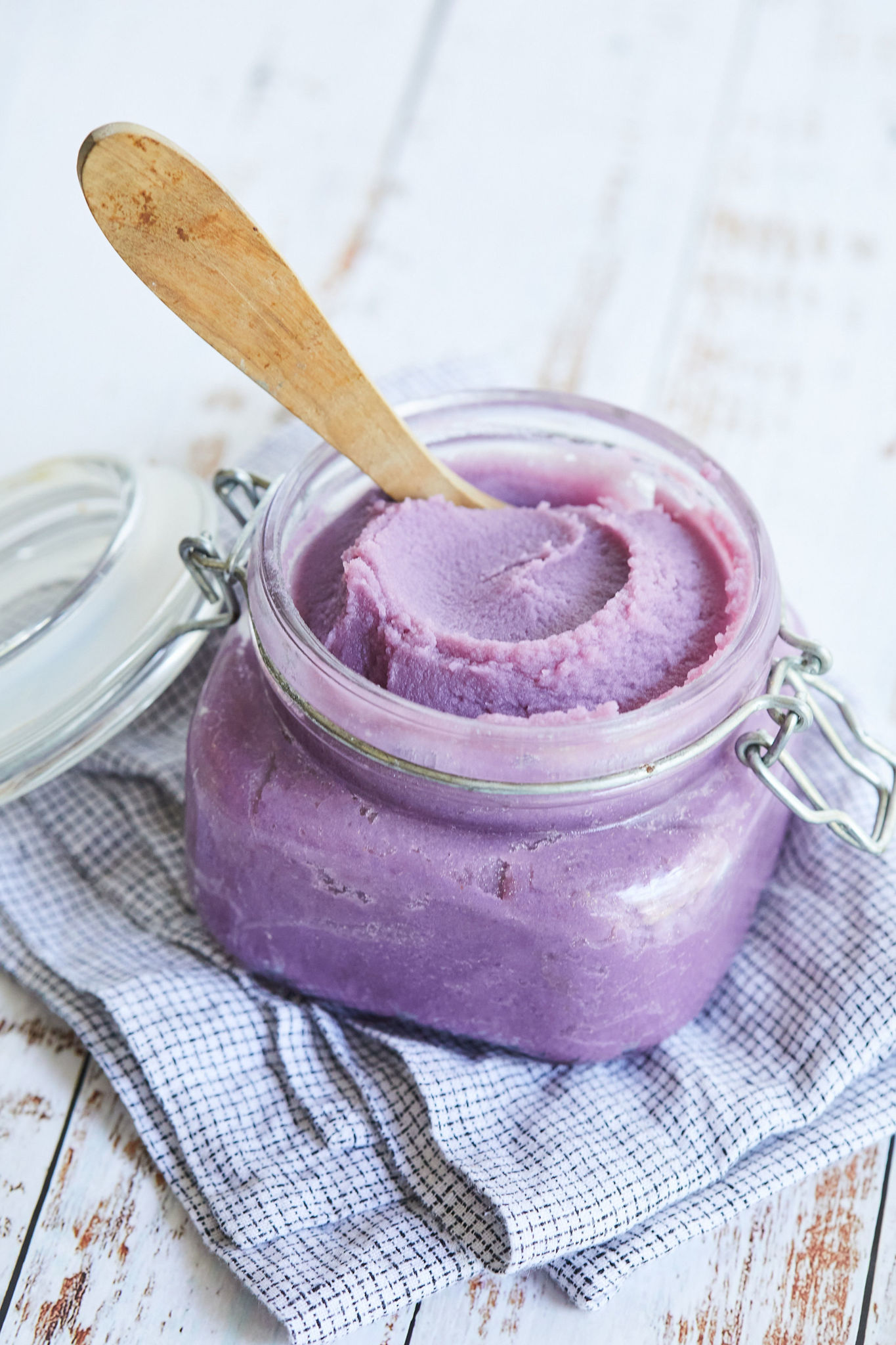 Ube Jam in a glass jar with a wooden spoon.