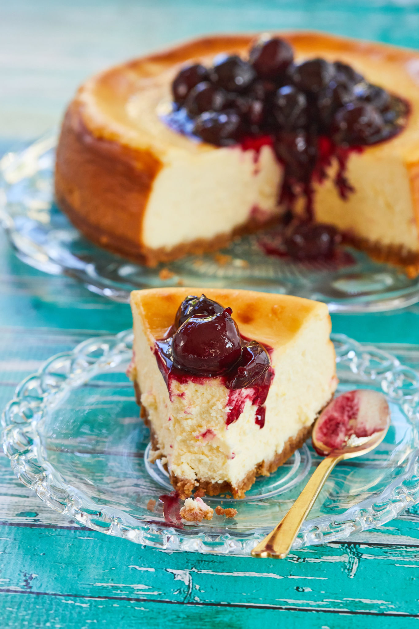 A slice of Best-Ever New York Cheesecake topped with cherries.