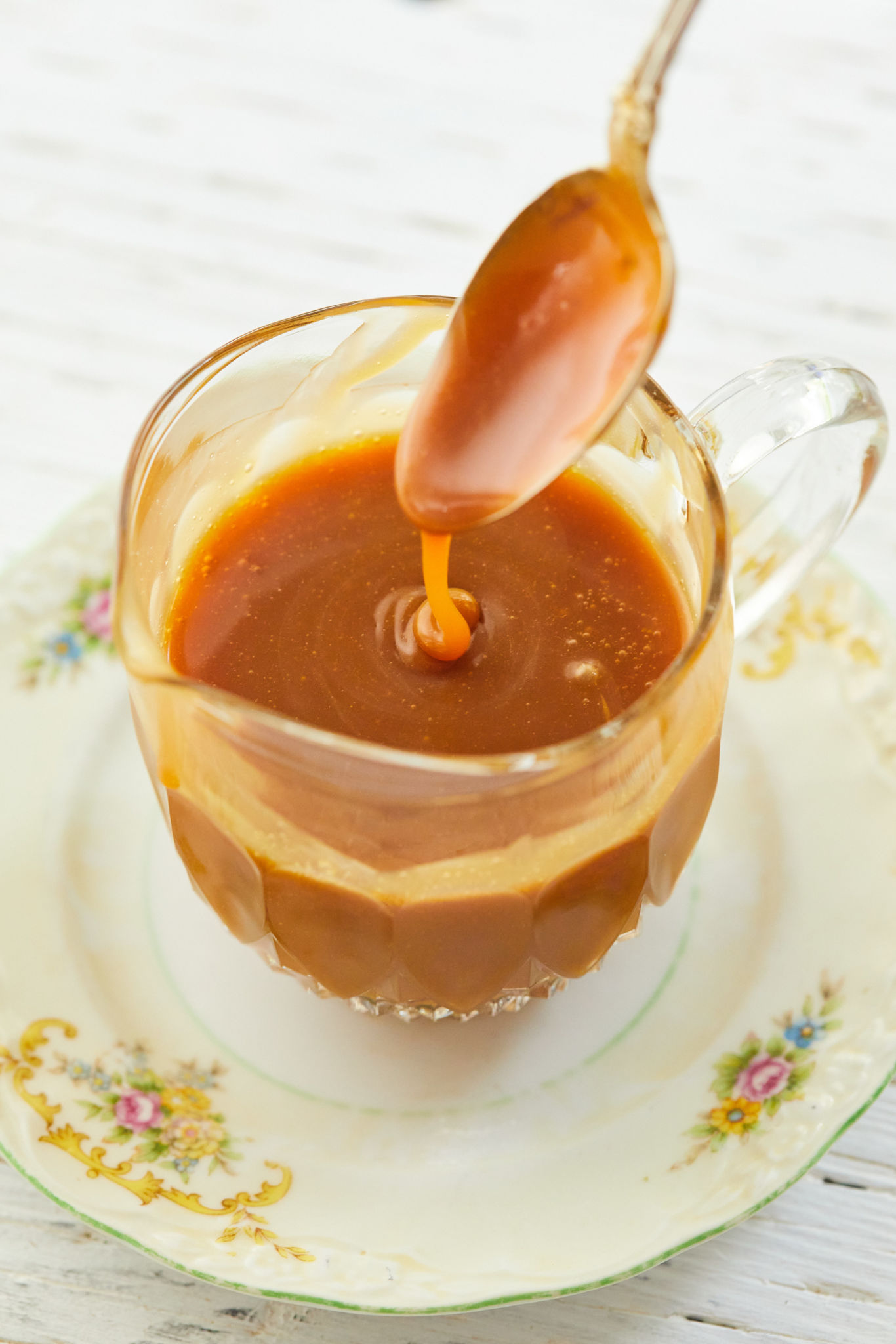 Spiced Rum Caramel Sauce running off a spoon into a glass.
