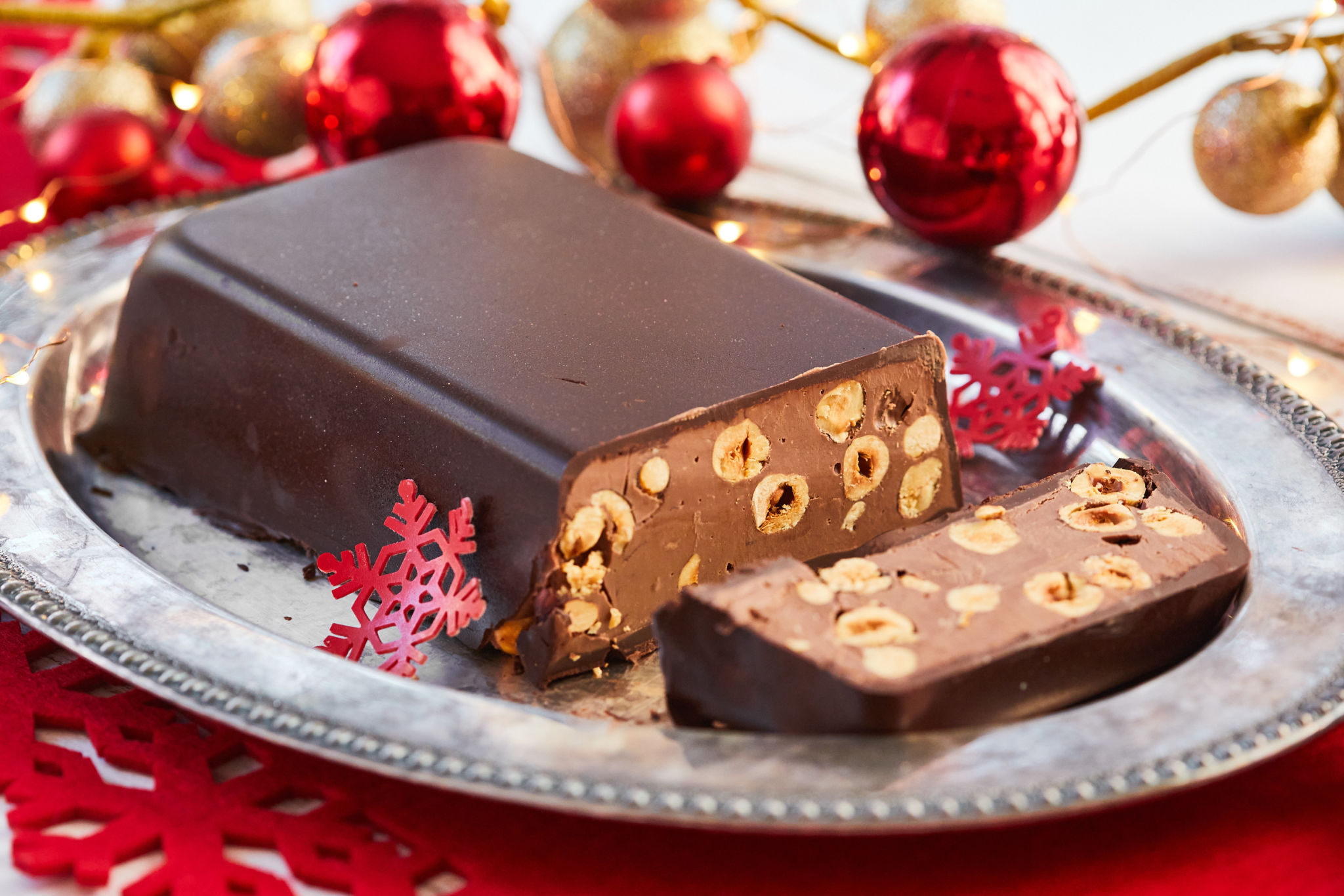 Chocolate & Hazelnut Torrone on a silver platter surrounded by holiday ornaments.