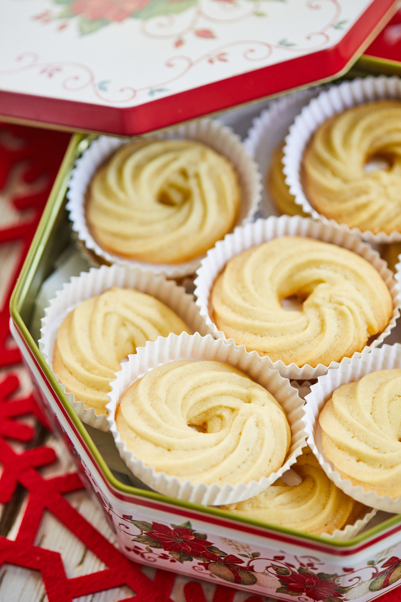 Homemade Danish Butter Cookies are presented in a Christmas tin. Each cookie has its own parchment paper holder. 