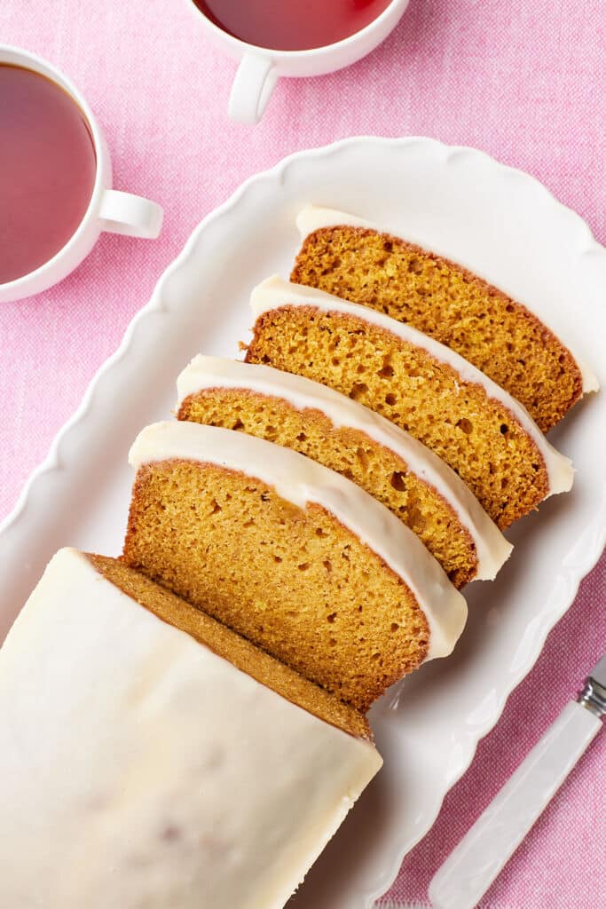 Best Pumpkin Bread is glazed and half of the loaf is sliced.