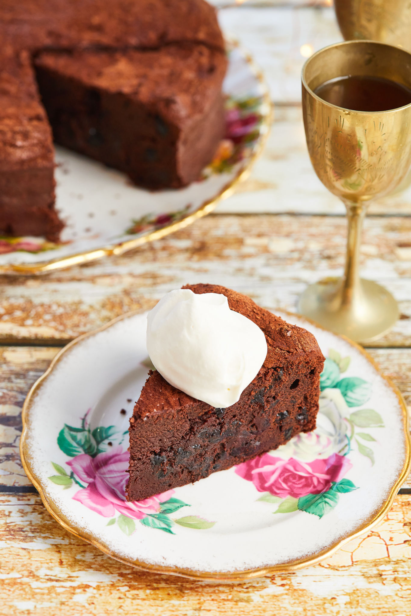 A dollop of whipped cream on top of a slice of Warm Chocolate Cake with Rum-Soaked Prunes.