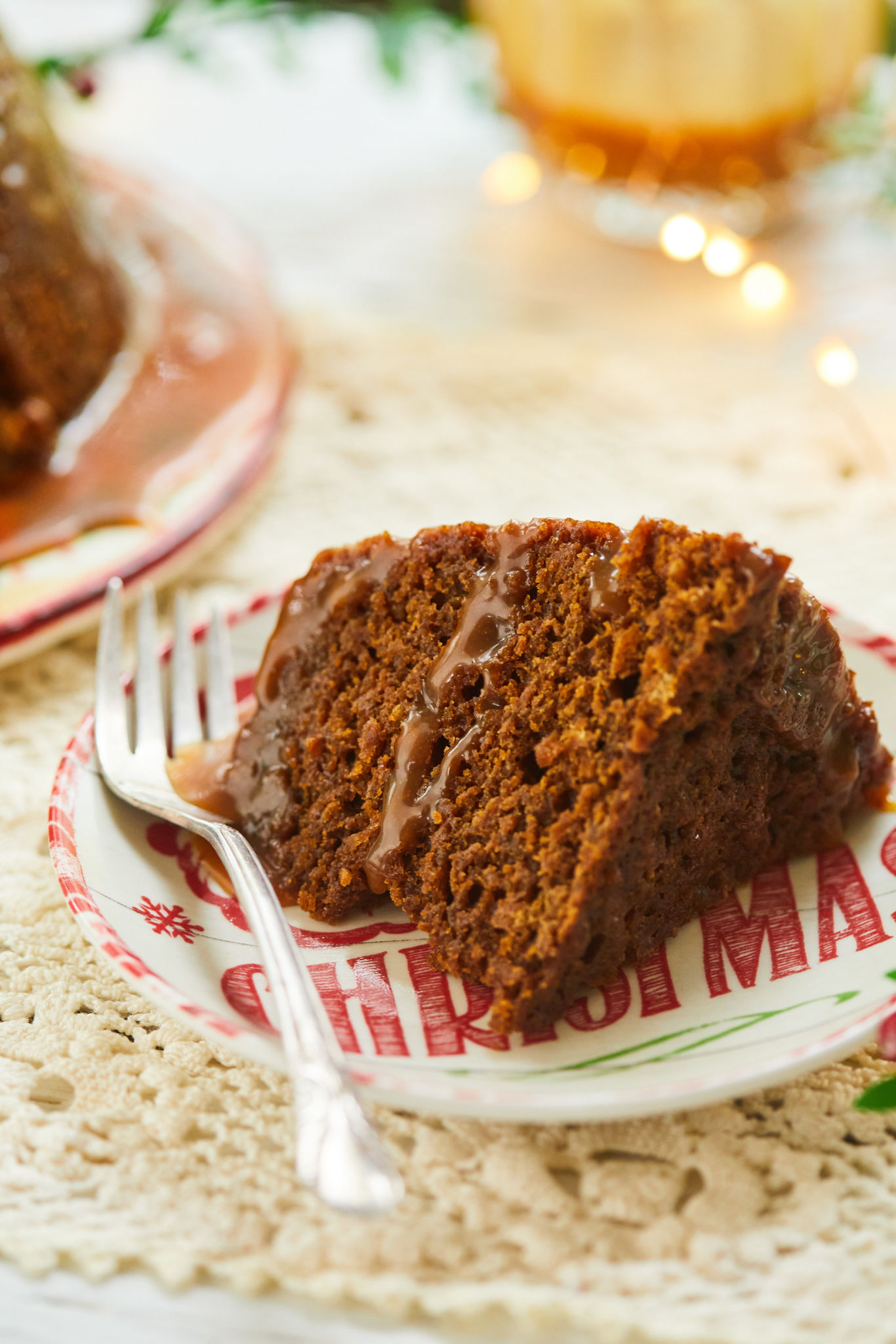 A slice of steamed gingerbread pudding on a plate with a fork.