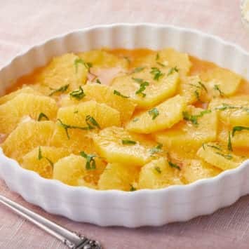 Sliced caramel oranges in a white serving dish.