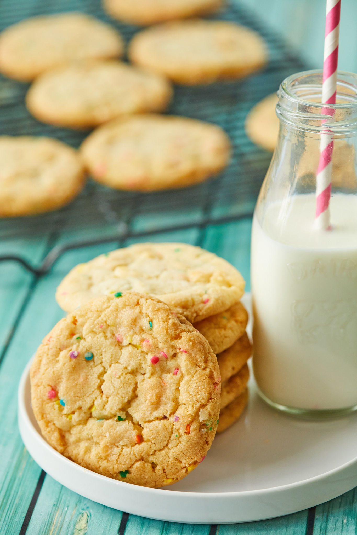 A stack of Funfetti cookies next to a glass of milk.