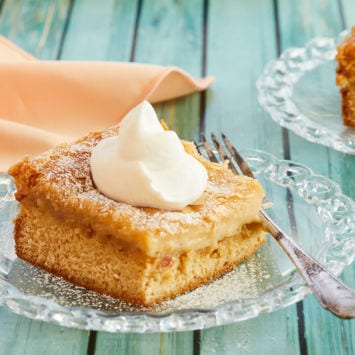A plate of gooey butter cake, topped with whipped cream.