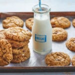 A tray of my Peanut Butter Chocolate Chip Cookies next to two jars of milk.