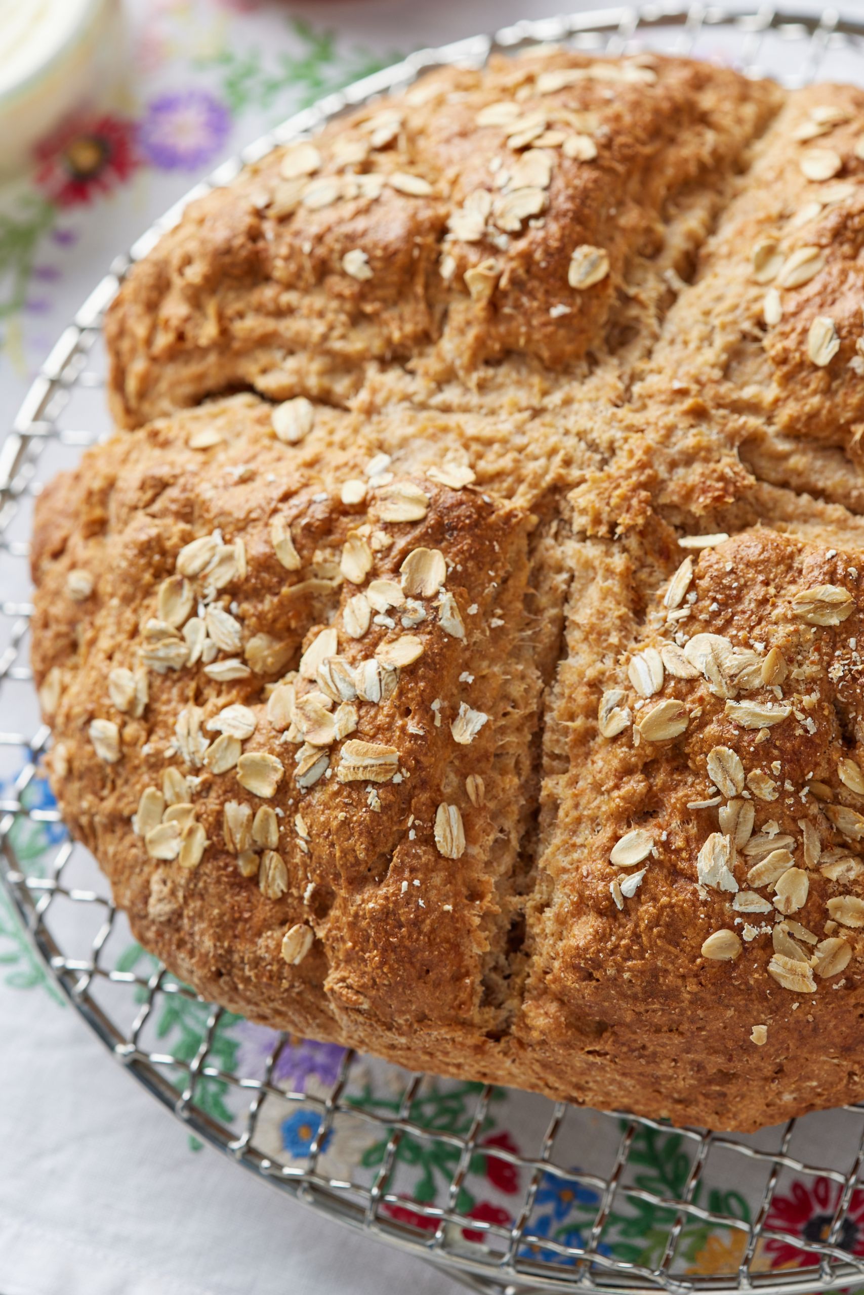 A big loaf of golden Irish soda bread with a cross scoring and topped with rolled oats. 