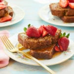 Plates of Banana Bread French Toast topped with syrup and strawberries.