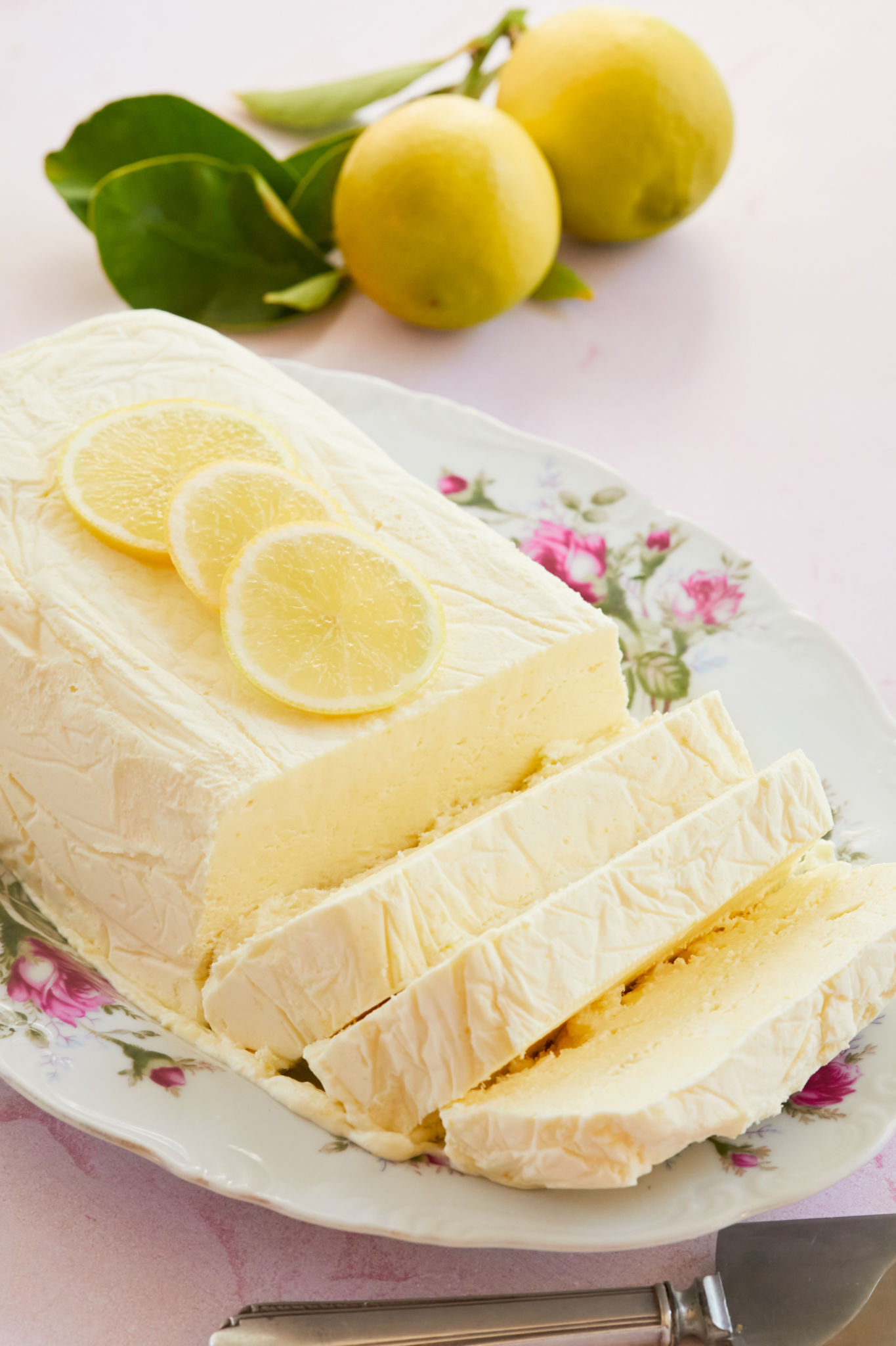 Lemon Semifreddo cut into thick, sweet slices, next to some whole lemons.