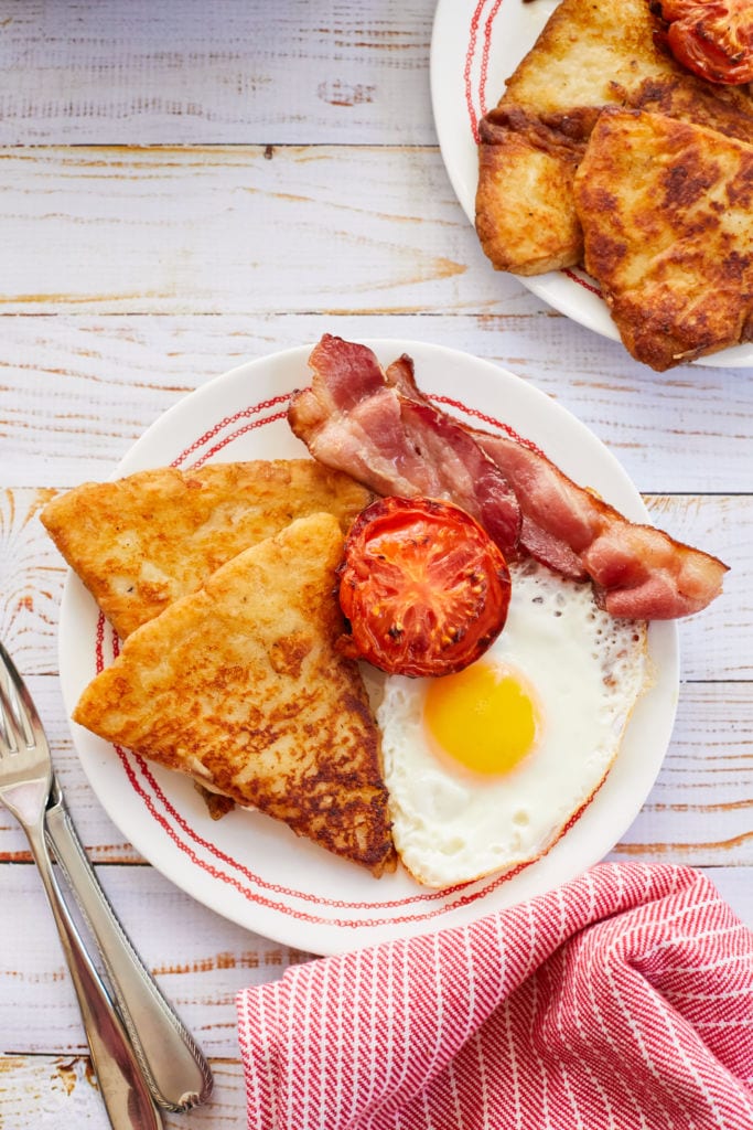 Golden crispy potato farls are served with bacon and tomato, eggs.