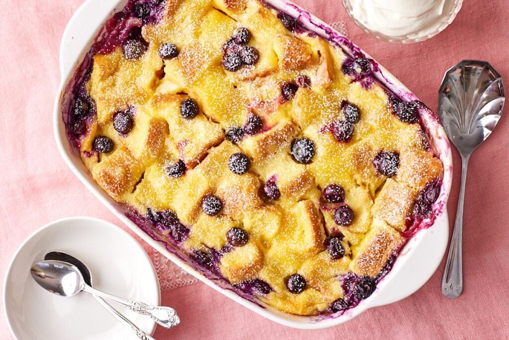 Top down view of a baking dish of golden lemon blueberry bread pudding.