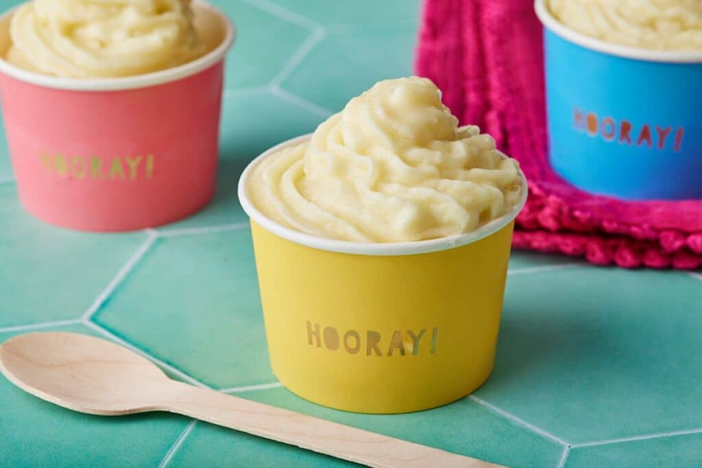 Soft smooth Dole Whip served in pink, yellow and red paper cups.
