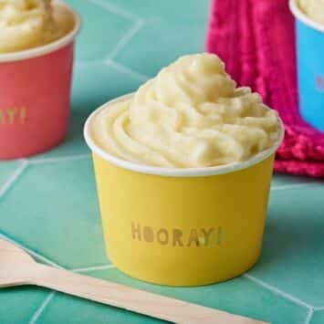 Soft smooth Dole Whip served in pink, yellow and red paper cups.