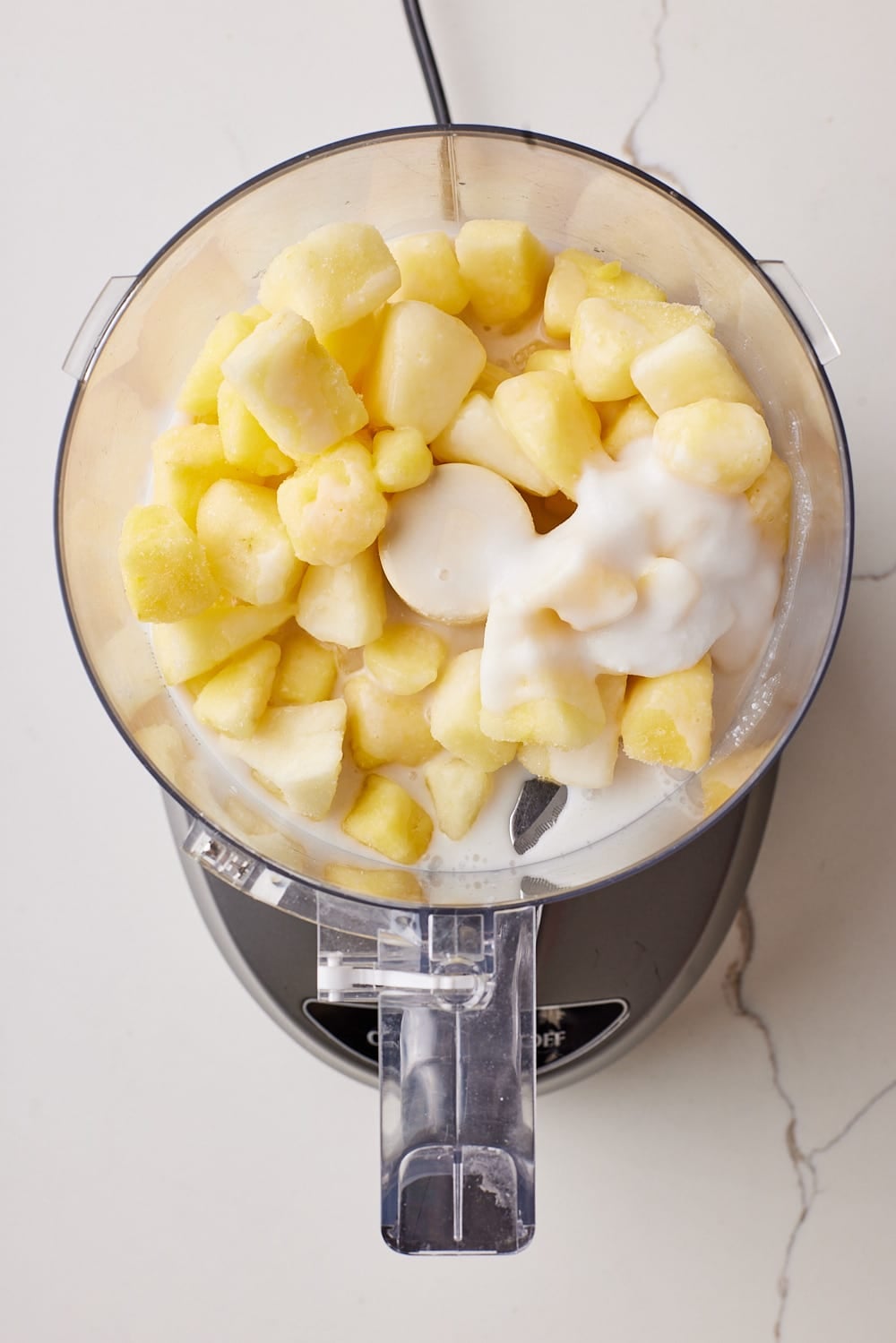 Frozen pineapple chunks and coconut milk are in the blender for Dole whip. 